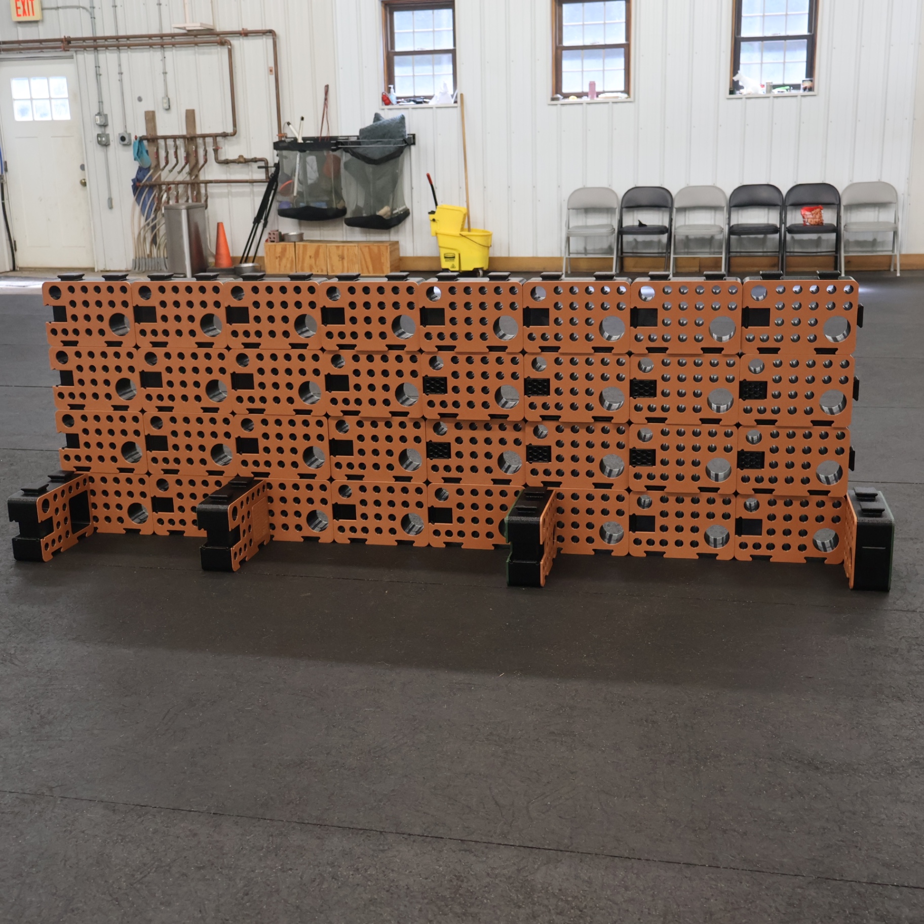 A long wall of orange and black D-Blocks with perpendicular blocks at the base, set up in a training facility